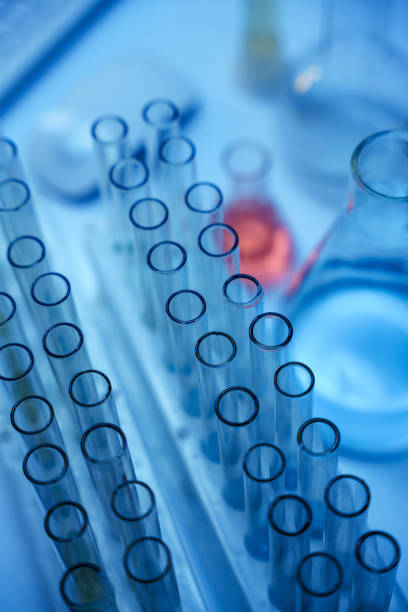 A top view on a glass test tubes in a test tube rack on a table with laboratory flasks next to it in a blue color scheme