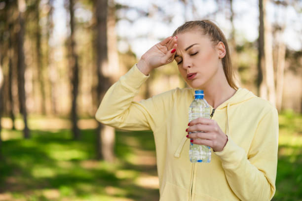 Tired woman  drinking water after exercise stock photo