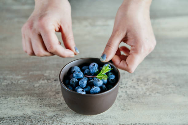 istock Female hands preparing bowl of blueberries and mint 1390321925