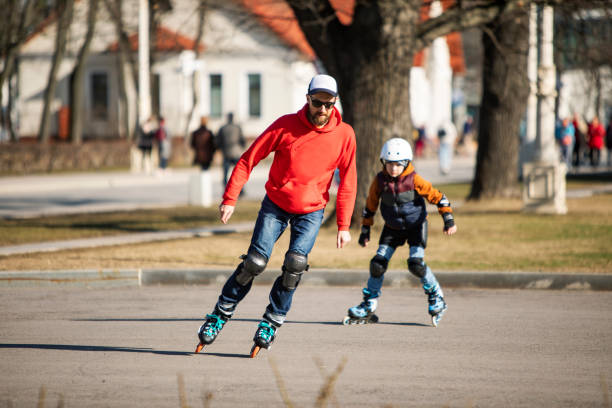 pai e filho patinam juntos em parque público - no rollerblading - fotografias e filmes do acervo