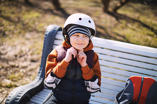 Little boy roller skating in public park in helmet and body protection