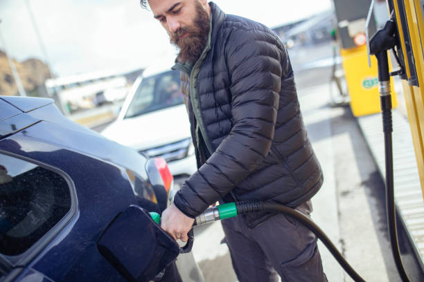 istock A bearded man in a winter jacket pours gasoline in a car. ISL 1390325713