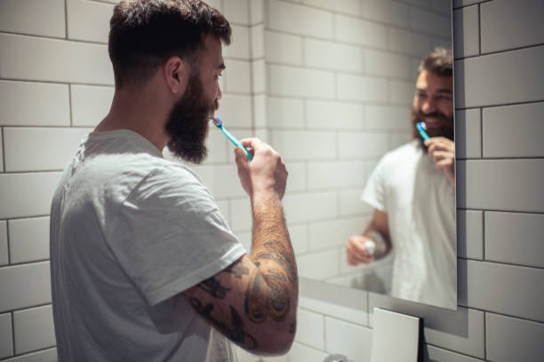 istock Looking in the mirror, a hipster man brushes his teeth. 1390325716
