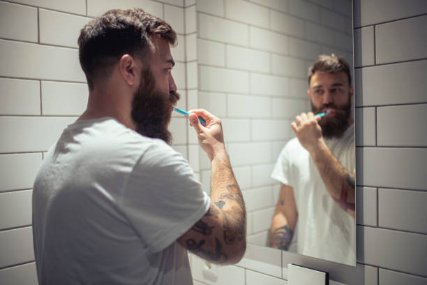 istock A millennial man brushes his teeth after waking up. 1390325950