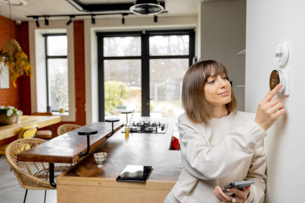 istock Woman controlling home temperature with electronic thermostat 1390326101