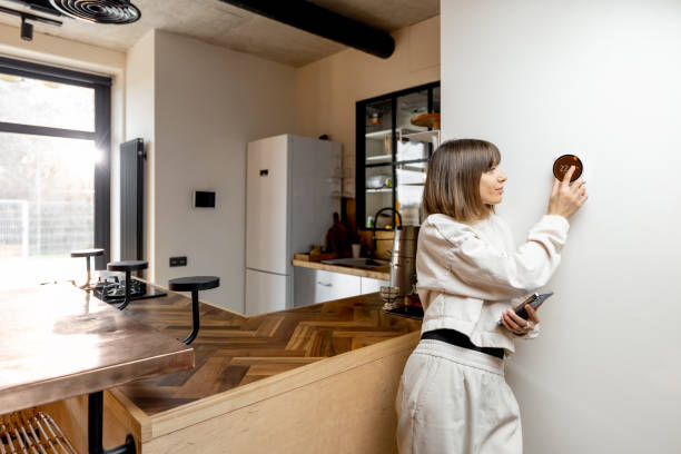 istock Woman controlling home temperature with electronic thermostat 1390326110