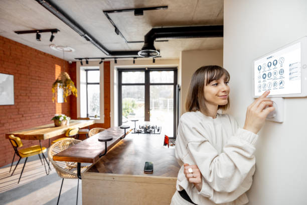 istock Woman controlling home devices with digital smart panel mounted on the wall 1390326118