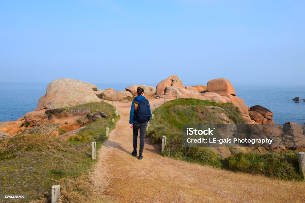 Young woman hiking trail on cote granite rose in Brittany, France Brittany - France Stock Photo