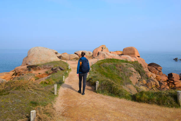 Young woman hiking trail on cote granite rose in Brittany, France Young woman hiking trail on cote granite rose in Brittany, France brittany france stock pictures, royalty-free photos & images