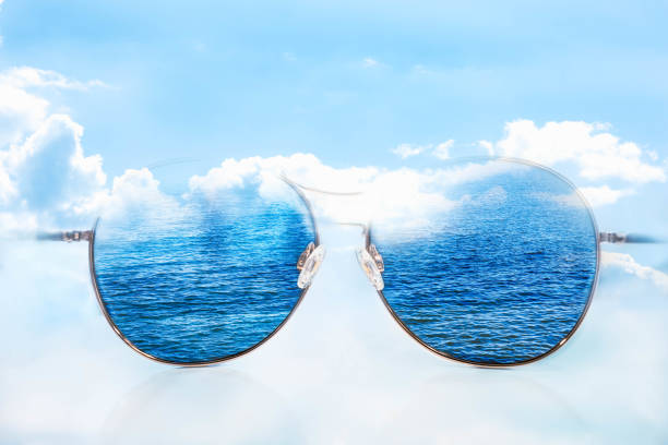 istock Sunglasses with deep blue ocean, cloudy blue sky through lens 1390326258