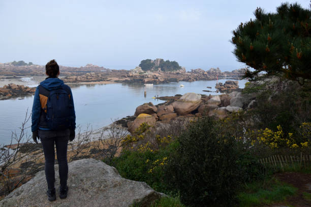 istock Woman standing on a boulder, looking out over water 1390326387