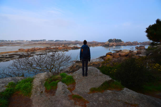 istock Woman standing on a boulder, looking out over water 1390326401