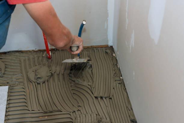 istock Applying adhesive with mason trowel over floor for ceramic tile 1390326490