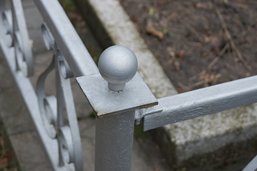 part of a gray metal decorative fence made of iron bars at the grave in the cemetery