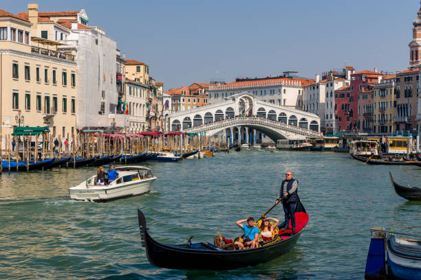 crowds of tourists and boats at the famous rialto bridge spanning the grand canal of the city of venice - market rialto bridge venice italy italy imagens e fotografias de stock