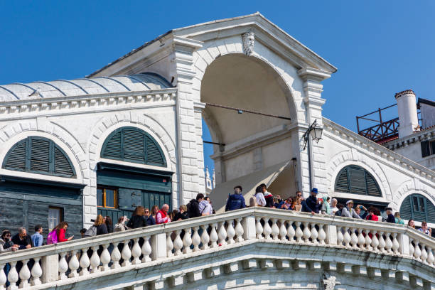 multidões de turistas e barcos na famosa ponte rialto que abrange o grande canal da cidade de veneza - market rialto bridge venice italy italy - fotografias e filmes do acervo