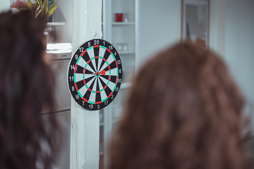 Small group of young teenager friends enjoy to playing darts together.