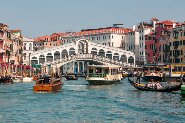 crowds of tourists and boats at the famous rialto bridge spanning the grand canal of the city of venice - market rialto bridge venice italy italy imagens e fotografias de stock