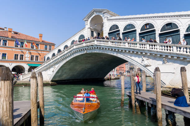 multidões de turistas e barcos na famosa ponte rialto que abrange o grande canal da cidade de veneza - market rialto bridge venice italy italy - fotografias e filmes do acervo