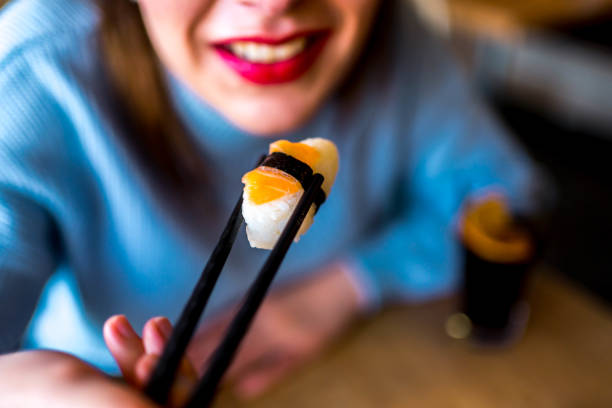 istock Woman taking tasty salmon sushi 1390334020