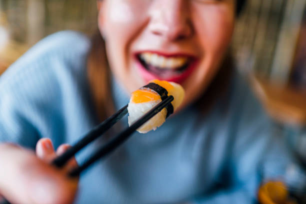istock Woman taking tasty salmon sushi 1390335228
