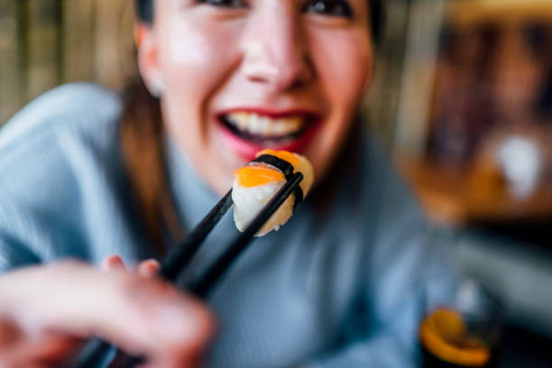 istock Woman taking tasty salmon sushi 1390335247