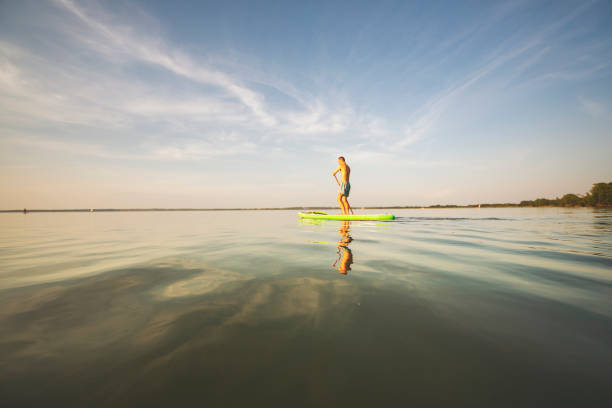 istock Young man swimming on sup boards alone at sunset 1390335312