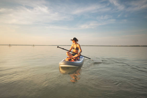 istock Young woman swimming on sup boards alone at sunset 1390335315