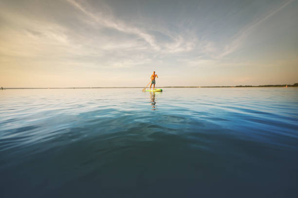 istock Young man swimming on sup boards alone at sunset 1390335343