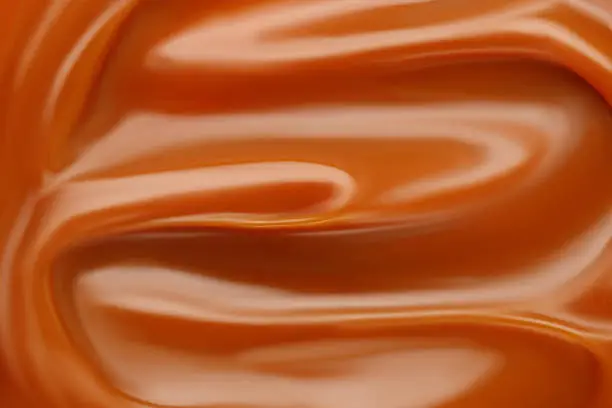 Photo of Liquid caramel syrup. Background of caramel paste. Texture Close up, top view.