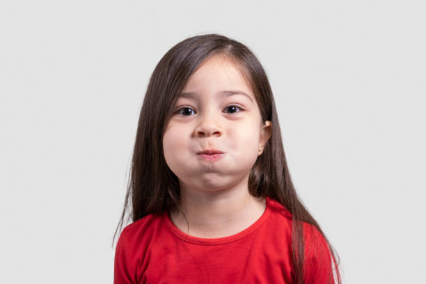 portret małej dziewczynki robiącej zabawną minę patrzącą na aparat na szarym tle - cross eyed making a face beautiful human face zdjęcia i obrazy z banku zdjęć