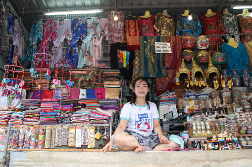 Young Thai woman selling traditional Thai merchandise at the Damnoen Saduak Floating Market