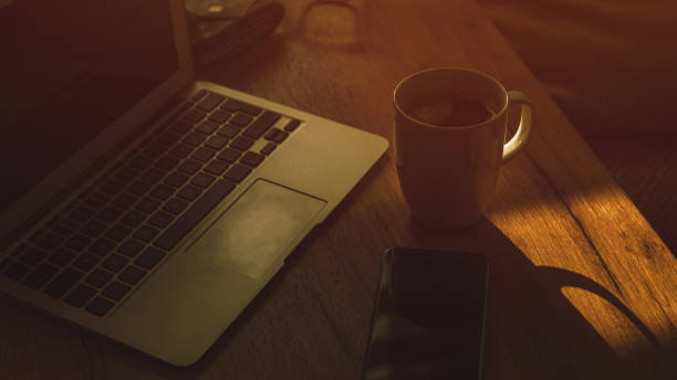 Morning coffee in dark home office interior, low key image with selective focus