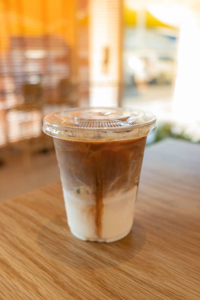 istock cold brewed iced latte coffee, showing separate in a layer the bottom as milk top by coffee shot in a plastic glass on wooden table in restaurant and cafe 1390345795