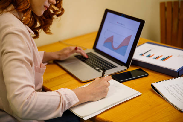 istock Businesswoman writing ideas while analyzing a graph on laptop 1390346692