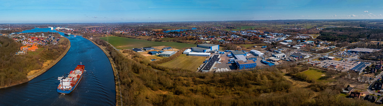 Panoramic aerial view of Kiel Canal with container ships and industrial park. Cargo ships on the Kiel Canal between Baltic sea and North Sea, Schleswig Holstein, Germany. Kiel Canal by Schacht-Audorf.