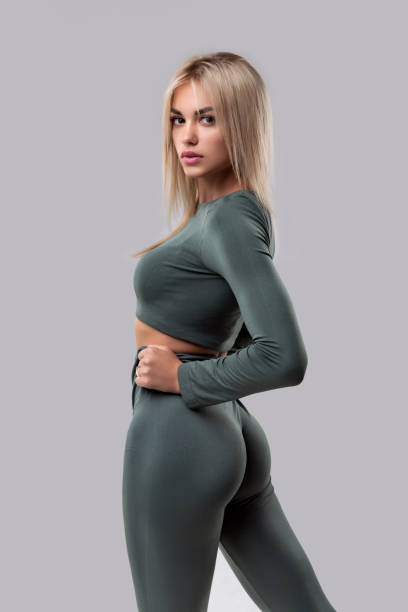 studio portrait of a beautiful girl with big buttocks in sportswear on a gray background. - förförisk kvinna bildbanksfoton och bilder