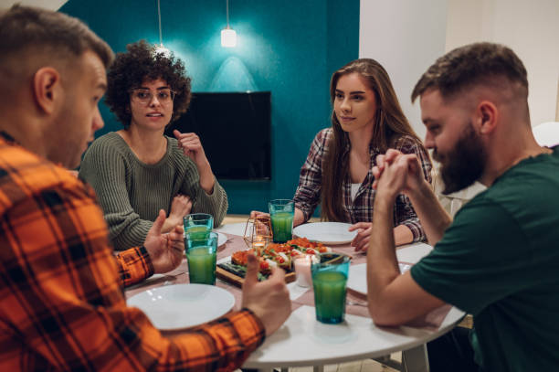 istock Group of friends enjoying dinner while sitting at the kitchen table together 1390353296