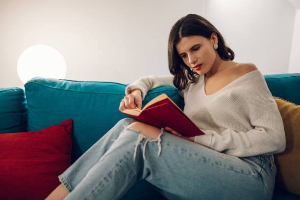 istock Woman reading a book while relaxing on a sofa at home 1390353301