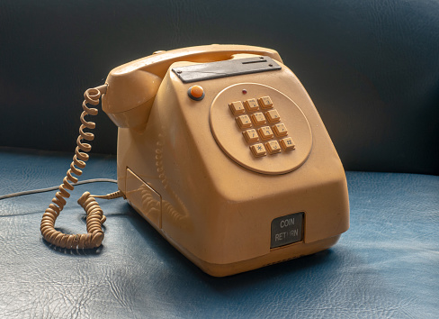 Old table version coin-operated public telephone, the kind used in bars and shops, yellow on a blue background.