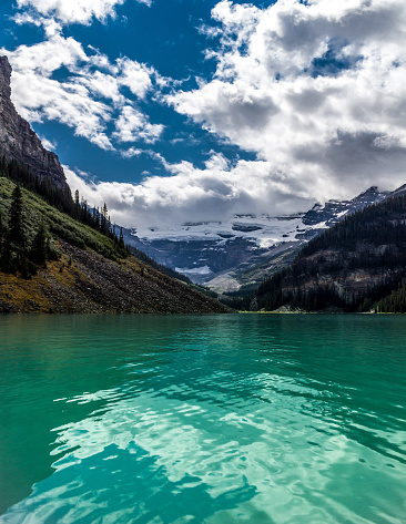 Crisp green waters of Lake Louise in Jasper, Alberta. Mountain lake landscape scenery until a blue sky with white clouds.