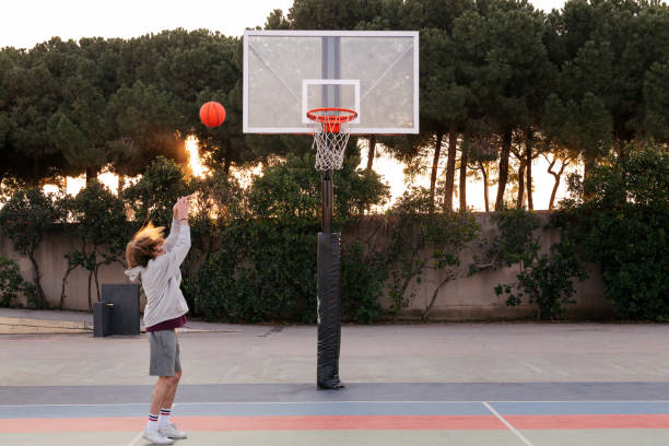 istock young man shooting baskets in a city park court 1390378432