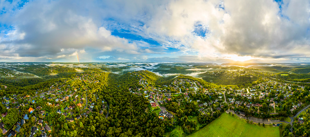 Panoramic view of Sydney northern suburb, over Mount Colah and Mount Kuring-Gai at Kuring-Gai National Park with storm clouds, sunrise and rainbow