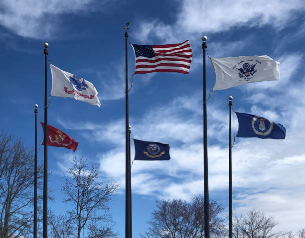 Military Memorial Flag Array The flags of all branches of the US military encircle the US flag at a veterans memorial public  park near Ocean City, MD with a stiff wind blowing them out straight us military stock pictures, royalty-free photos & images