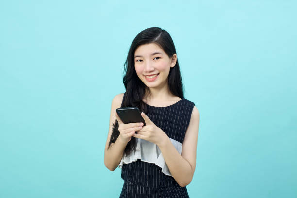 istock Surprised young Asia lady using mobile phone with positive expre 1390391252
