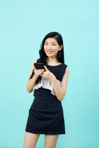 istock Surprised young Asia lady using mobile phone with positive expre 1390391263
