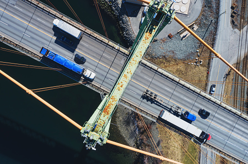 Aerial drone view of truck traffic on a suspension bridge.