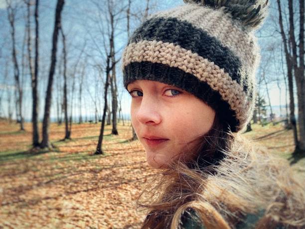 Portrait of teen girl in hat, outdoors on a fall day in Presque Isle Park in Marquette, Michigan in The Upper Peninsula of Michigan. stock photo