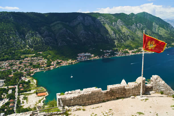 the flag of montenegro develops in the wind. view from the kotor fortress - karadağ bayrağı stok fotoğraflar ve resimler