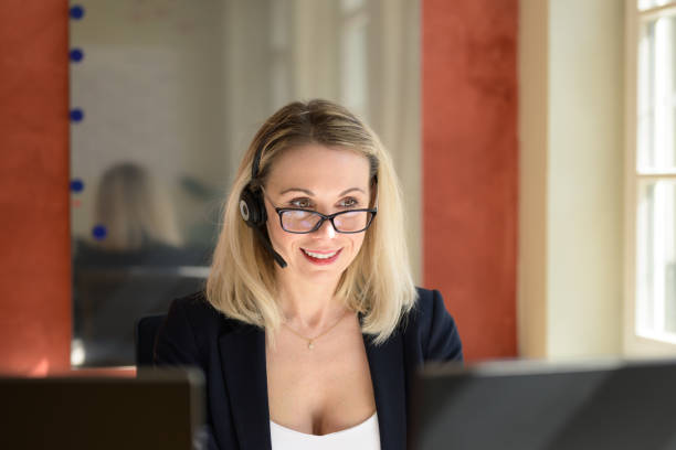 istock Business woman with eyeglasses using headset in office reading information 1390417441